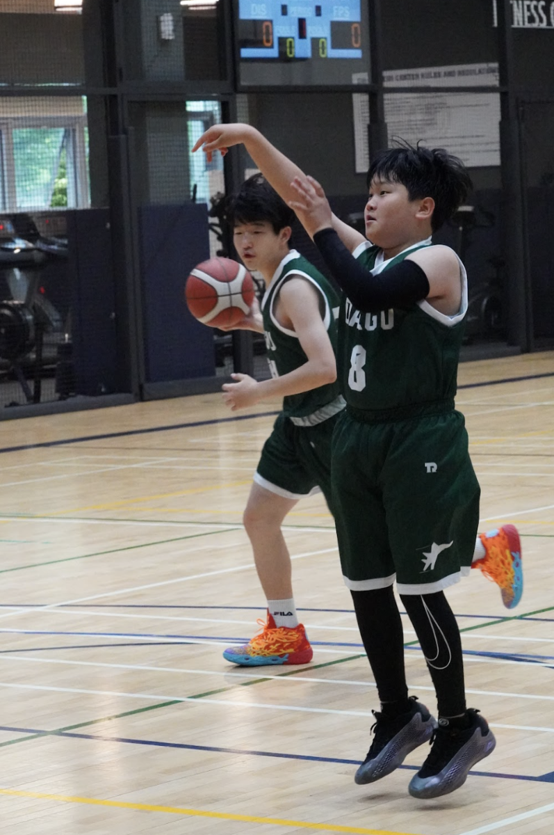 Seventh grader Joseph Beck (8) practices his jump shot during pre-game warm-ups. With focused energy and crisp form, he repeatedly drills shots from his sweet spot on the court. 